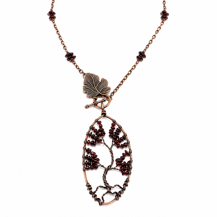 Copper wire tree of life pendant with red garnet beads on a matching chain with a leaf-shaped toggle clasp.