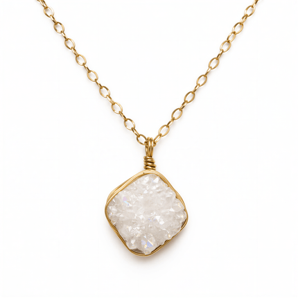 White druzy gemstone necklace with a square wire-wrapped gold metal pendant on a gold link chain.